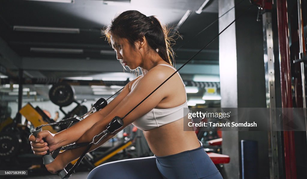Sportliche Frau, die auf der Multistation im Fitnessstudio für Arm- und Schultermuskeln trainiert. Fitnesstraining im Fitnessstudio.