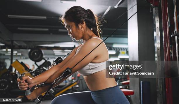 sporty woman exercising on multistation at gym for arm and shoulders muscles. fitness exercising in gym. - asian female bodybuilder 個照片及圖片檔