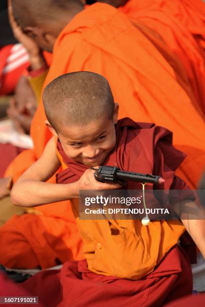 Young Buddhist monk plays with a toy gun during the fourth day of a teaching session led by Tibetan spiritual leader The Dalai Lama at The Kalachakra...