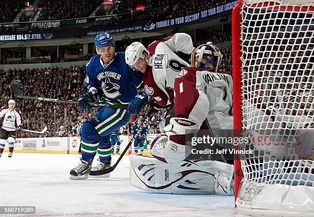 Maxim Lapierre of the Vancouver Canucks and Jan Hejda of the Colorado Avalanche look on as Semyon Varlamov of the Colorado Avalanche makes a save...