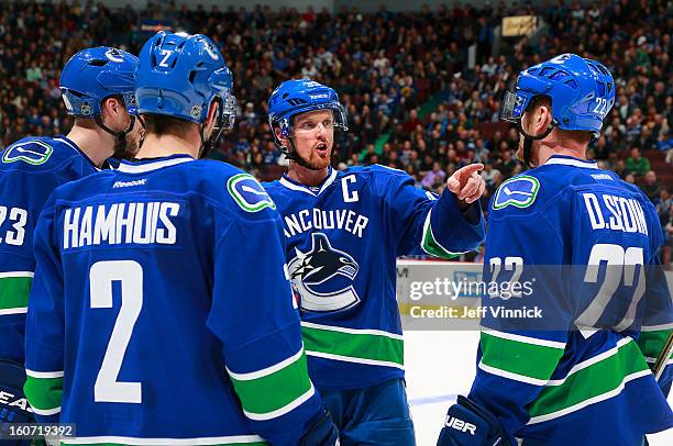 Henrik Sedin of the Vancouver Canucks talks to teammates Alexander Edler, Dan Hamhuis and Daniel Sedin during their NHL game against the Colorado...