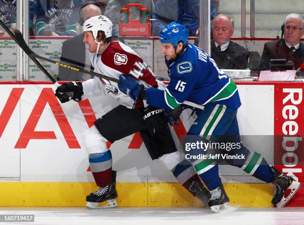 Aaron Volpatti of the Vancouver Canucks and Ryan Wilson of the Colorado Avalanche race up the boards during their NHL game at Rogers Arena January...