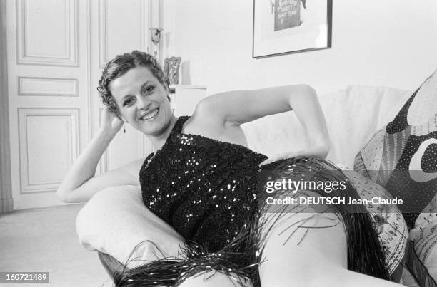 Rendezvous With Anne Jousset. Le 17 avril 1980, l'actrice Anne JOUSSET chez elle, posant souriante sur un canapé en robe du soir courte, en tissu...