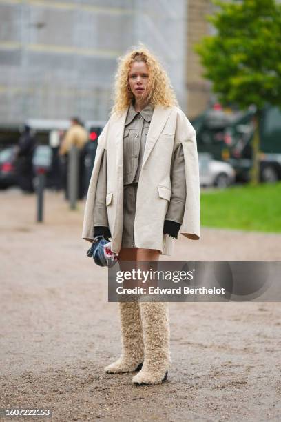 Guest wears a beige blazer jacket, a pale gray shiny leather buttoned jacket, a matching pale gray shiny leather zipper short skirt, beige sheep fur...