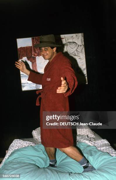 Rendezvous With Michel Boujenah. Novembre 1985- Portrait de Michel BOUJENAH chez lui sur le lit en peignoir, chaussettes et chapeau sur la tête.