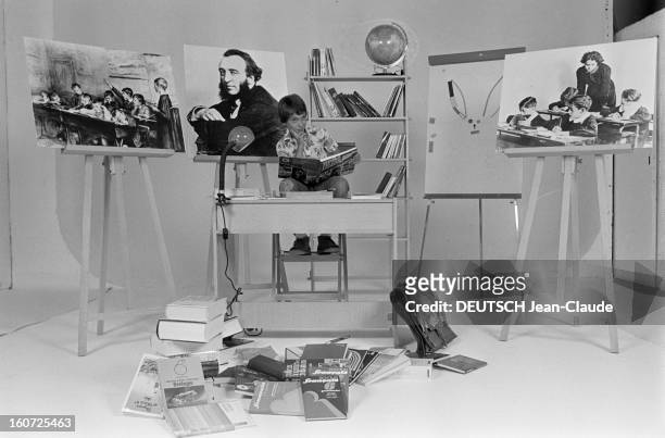 Education - School Supplies. Paris- 8 Septembre 1977- Enseignement et fournitures scolaires: un jeune garçon pose assis à un bureau scolaire, un...