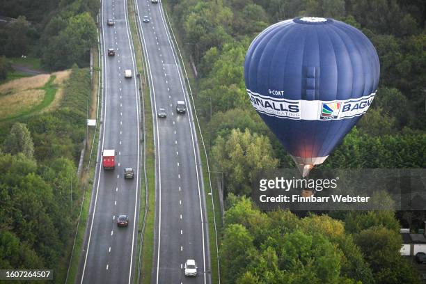 Balloon flies over a dual carriageway in Bristol during a mass ascent on August 11, 2023 in Bristol, England. The Bristol International Balloon...