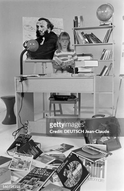 Education - School Supplies. Paris- 8 Septembre 1977- Enseignement et fournitures scolaires: une fillette pose assise à un bureau scolaire, lisant un...