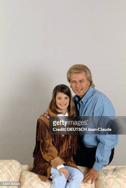 Thierry Roussel And Daughter Athina Pose In Studio. Portrait de Thierry ROUSSEL, avec sa fille Athina, avec une veste western à franges, assis sur le...