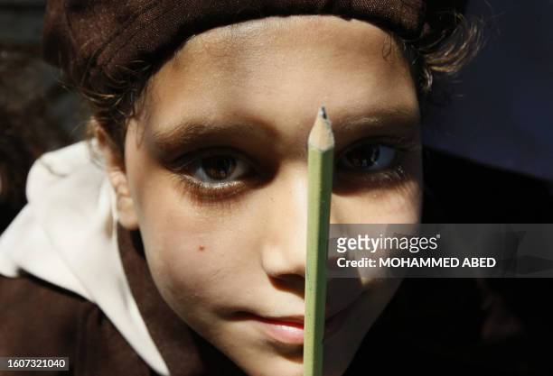Palestinian schoolgirl holds a pencil as she attends a protest outside the headquarters of the United Nations in Gaza City on September 8, 2009 to...