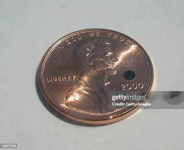 An image of a 2 mm Artificial Silicon Retina chip, created by Optobionics Corp., on top of a penny August 6, 2001 in Wheaton, IL. Through the...