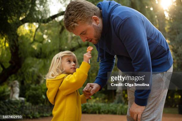 baby girl sharing sweet food with father in park. generosity, kindness concept - kind 個照片及圖片檔