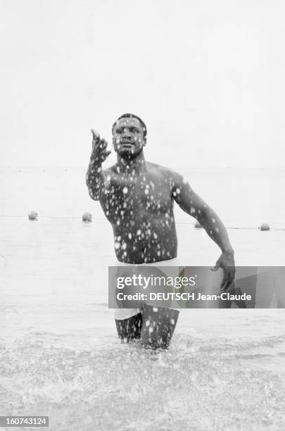 Singing Tour Of Joe Frazier Boxing World Champion. Près de Nice, sur une plage, Joe FRAZIER, en maillot de bain, debout dans l'eau, faisant des...
