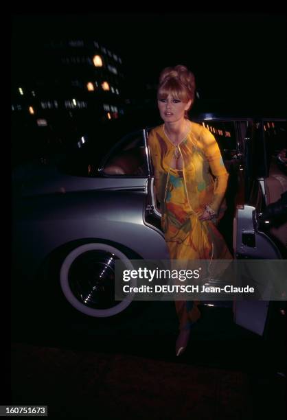 Gala Of The Union Of Artists 1966. Paris - 21 mars 1966 - L'actrice Brigitte BARDOT, vêtue d'une robe décolletée jaune à motif fleuri, sort d'une...