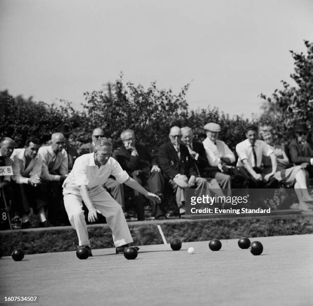 Man bends down in front of several bowls during the English Bowls Championship, Mortlake, Surrey, August 24th, 1959.