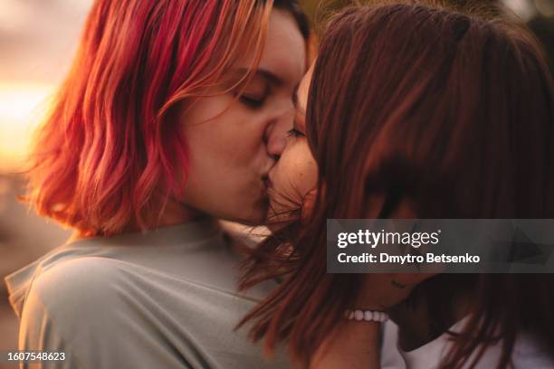 lesbian couple kissing at sunset during summer - beso en la boca fotografías e imágenes de stock