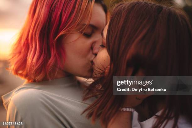 lesbian couple kissing at sunset during summer - embrasser sur la bouche photos et images de collection