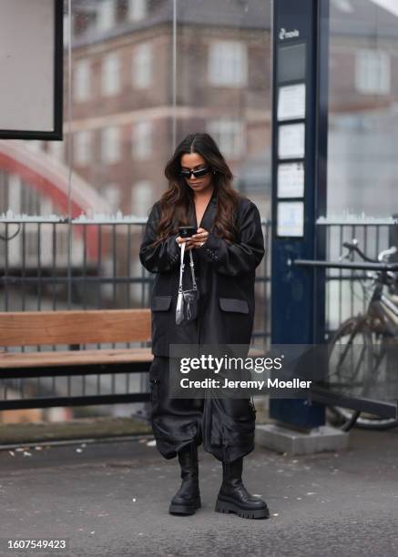 Naomi Anwer seen wearing black sunglasses, silver earrings, black oversized blazer, matching black cargo pants, silver metallic bag and Copenhagen...