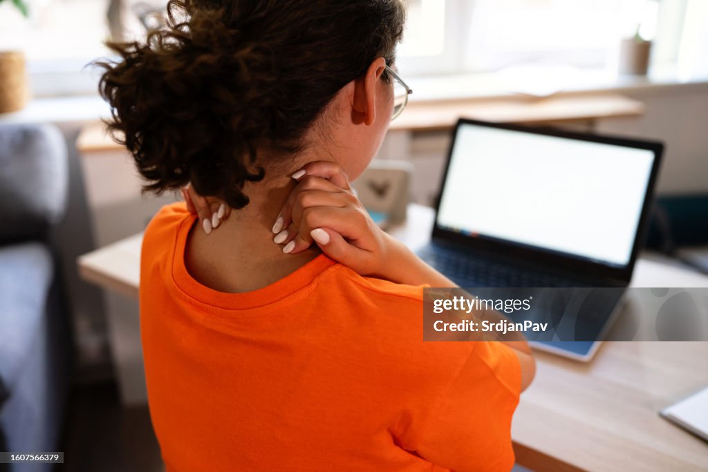 Femme méconnaissable souffrant de maux de cou, alors qu’elle travaille à domicile