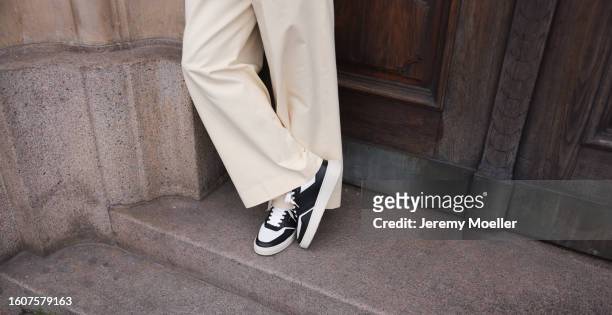 Jean Claude Mpassy seen wearing black sunglasses, white / navy print pattern shirt, cream white pants and Copenhagen Studios CPH1M Leather Mix Black...