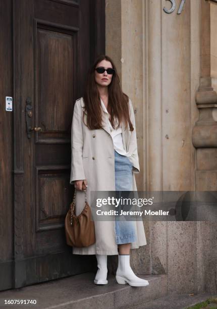 Annabel Rosendahl seen wearing black sunglasses, white shirt, beige long coat, light blue denim skirt, brown leather bag and Copenhagen Studios...