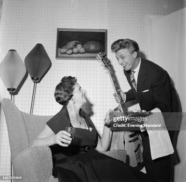 British singer Tommy Steele offering a platter of food to his mother Betty, London, September 5th 1958. Steele has recently bought a new house for...