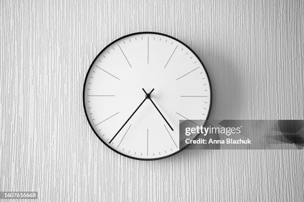 modern minimalist black and white clock on white wall - wanduhr stock-fotos und bilder