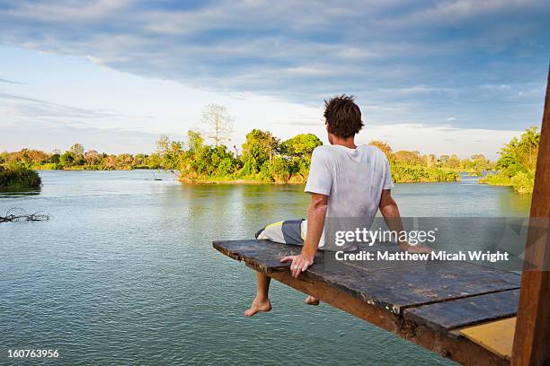 a man sits atop a high diving plank - river mekong stock pictures, royalty-free photos & images