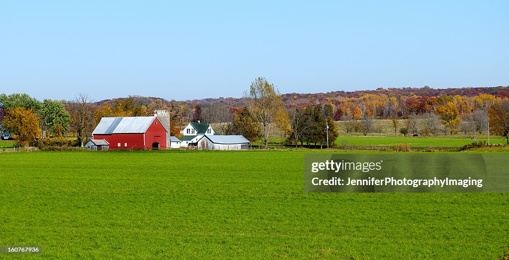 Landscape view of red Midwestern dairy farmhouse and land