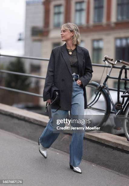 Sonja Leigh seen wearing black sunglasses, gold necklace, grey t-shirt, grey striped blazer jacket, light blue denim pants, black leather belt, black...