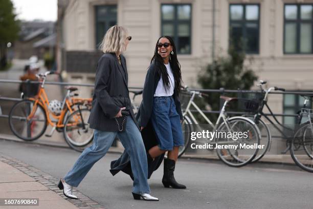 Sonja Leigh seen wearing black sunglasses, gold necklace, grey t-shirt, grey striped blazer jacket, light blue denim pants, black leather belt, black...