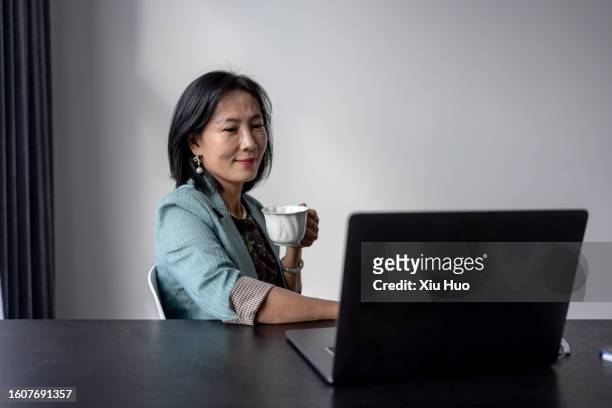 asian businesswoman is drinking coffee in front of her laptop - 活動 stock pictures, royalty-free photos & images