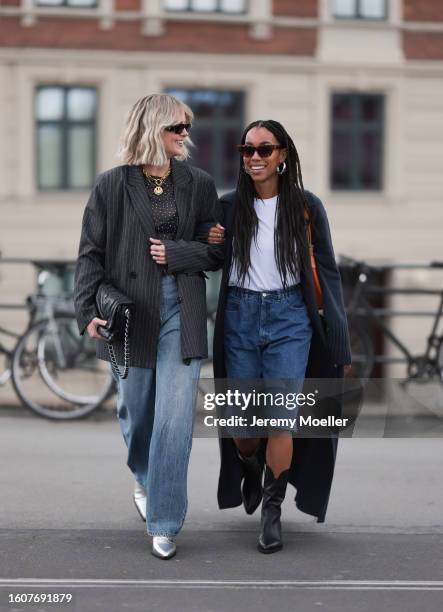 Sonja Leigh seen wearing black sunglasses, gold necklace, grey t-shirt, grey striped blazer jacket, light blue denim pants, black leather belt, black...