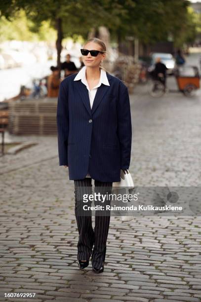 Tine Andrea wears black pants, a white shirt, and a navy blue oversized jacket outside Remane during the Copenhagen Fashion Week Spring/Summer 2024...