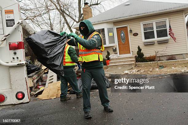 Sanitation workers thrrow out debris from a flood damaged home in Oakwood Beach in Staten Island on February 5, 2013 in New York City. In a program...