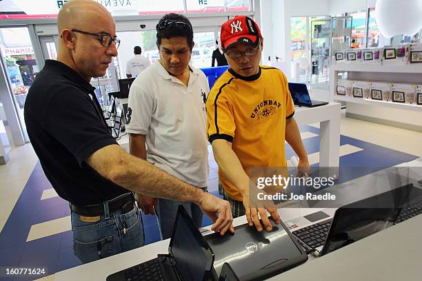 Wolmer Santiago shows a Dell computer to Francis Valis and Ariel Labella display at the Electric Avenue store on February 5, 2013 in Miami, Florida....