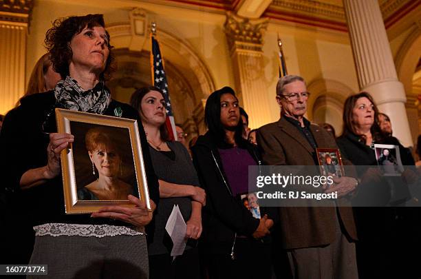 Jane Dougherty, left, holds a photo of her sister, Mary Sherlach, who was killed at Sandy Hook, during a press conference to unveil gun legislation...