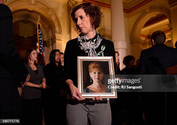 Jane Dougherty holds a photo of her sister, Mary Sherlach, who was killed at Sandy Hook, during a press conference to unveil gun legislation aimed at...