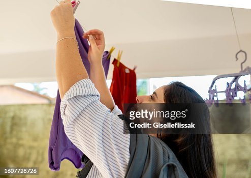 Woman hanging clothes to dry on a line at home