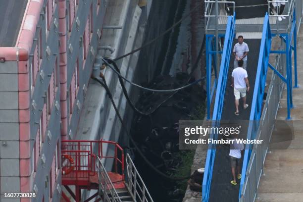 People are seen on the gangway of the Bibby Stockholm immigration barge in Portland Port, on August 11, 2023 in Portland, England. More than three...