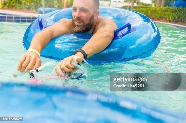 happy smiling man on an inflatable pool float at a resort swimming pool or water park - dad body stock pictures, royalty-free photos & images