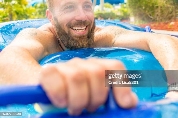 happy smiling man on an inflatable pool float at a resort swimming pool or water park - dad body stock pictures, royalty-free photos & images