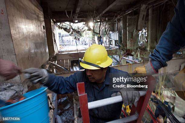 Worker climbs a ladder to bring up some rubble during cleanup operations at the Petroleos Mexicanos headquarters building in Mexico City, Mexico, on...