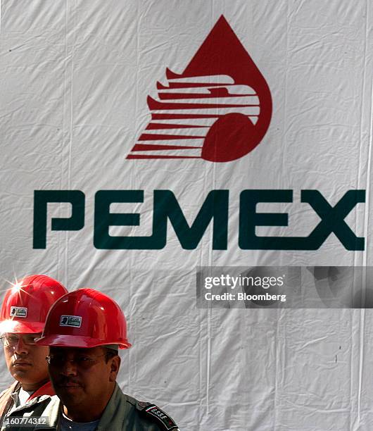 Workers stand next to a banner with the Petroleos Mexicanos logo on it at the blast site at company headquarters in Mexico City, Mexico, on Tuesday,...
