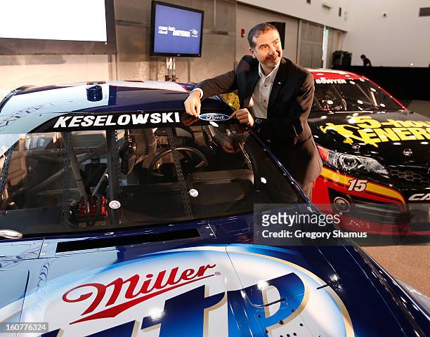 Jamie Allison, director of Ford Racing places a Ford sticker on the windshield of the Miller Light Ford driven by Brad Keselowski after a breakfast...