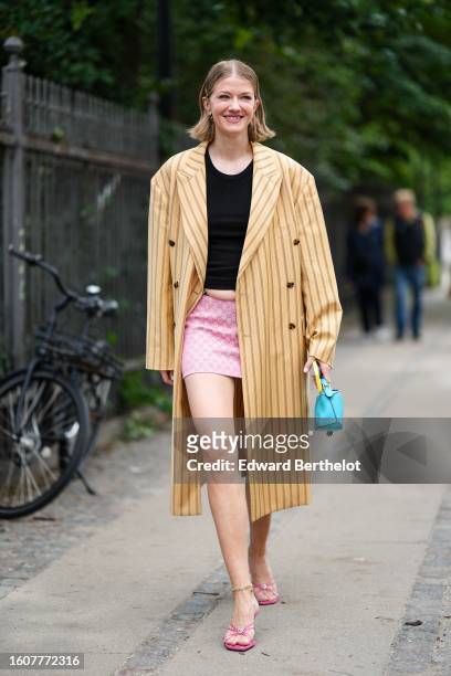 Marianne Theodorsen wears a black t-shirt, a pale yellow and black small striped print pattern long oversized blazer coat, a pale pink GG monogram...