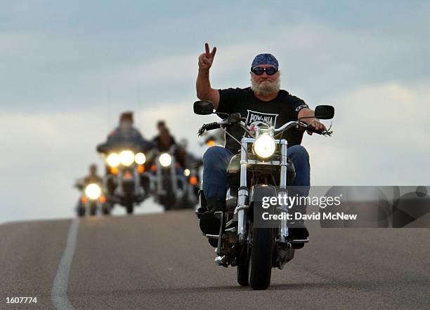 Motorcylist gives a hand signal while on a run near Devils Tower National Monument, WY which is one of many popular destinations for cyclists...