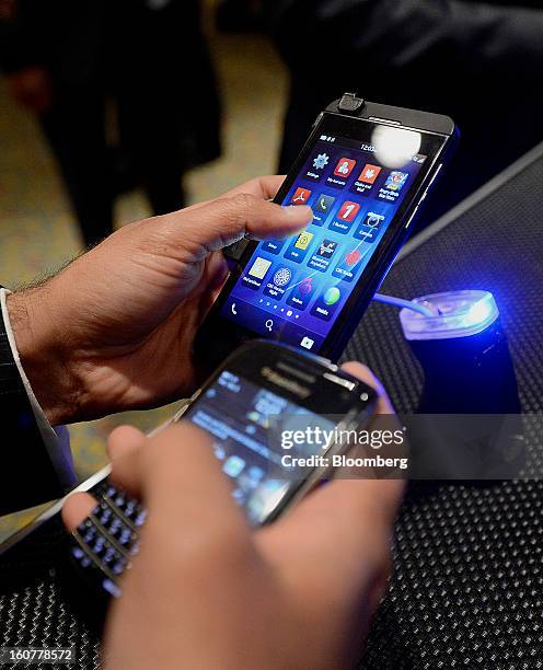 An attendee compares the BlackBerry Z10, top left, with another device during an event at the Empire Club of Canada in Toronto, Ontario, Canada, on...