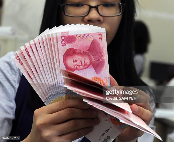 Taiwan's Mega Bank staff counts Chinese yuan banknotes in Taipei on February 6, 2013. Taiwanese banks started allowing customers to open Chinese yuan...