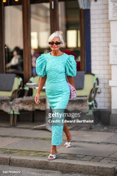 Grece Ghanem wears black sunglasses, a mint green embossed ruffled puffy short sleeves / long tube dress, a white / pink / blue tweed handbag from...